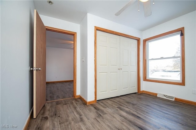 unfurnished bedroom featuring baseboards, a closet, visible vents, and dark wood-type flooring