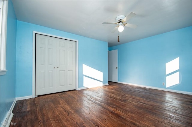 unfurnished bedroom with a closet, a ceiling fan, a baseboard heating unit, wood finished floors, and baseboards