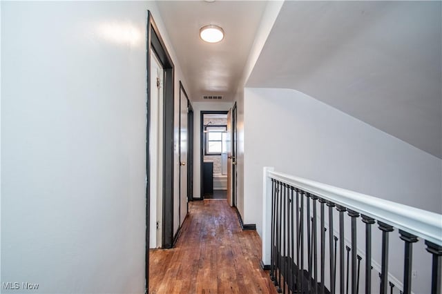 corridor with dark wood-style flooring, visible vents, and vaulted ceiling