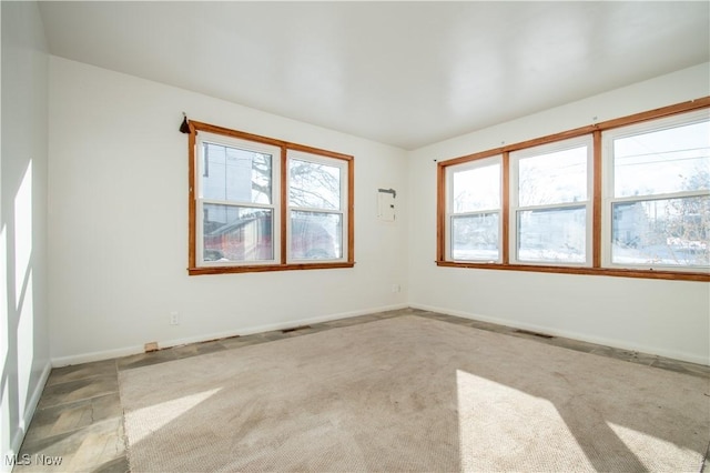 spare room featuring carpet, visible vents, and baseboards