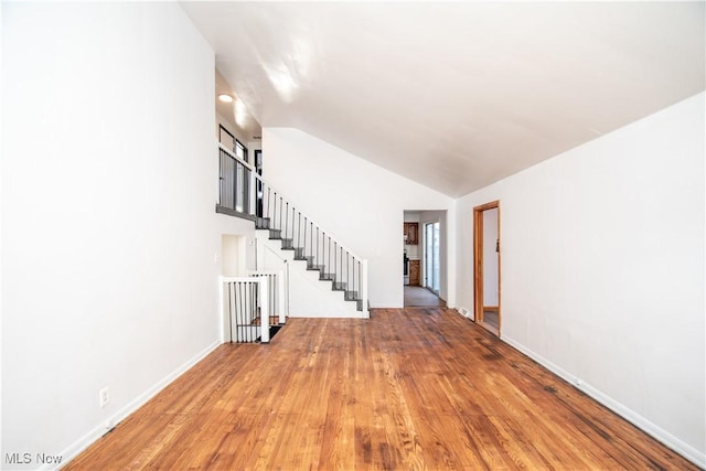 interior space featuring vaulted ceiling, stairway, baseboards, and wood finished floors