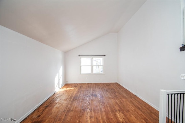 spare room featuring lofted ceiling, radiator heating unit, baseboards, and wood finished floors