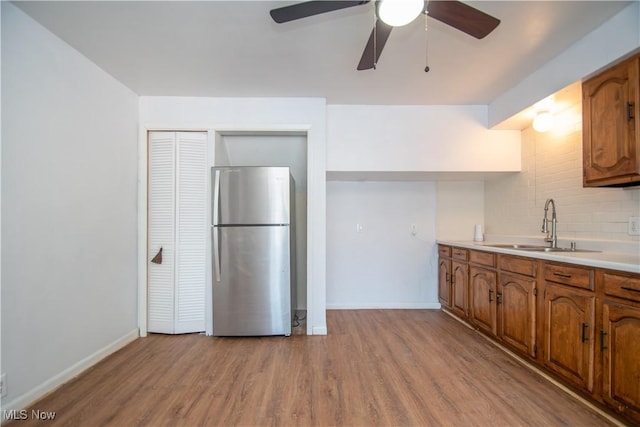 kitchen with brown cabinetry, freestanding refrigerator, light countertops, and decorative backsplash