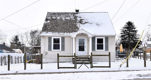 view of front facade with a shingled roof and a fenced front yard