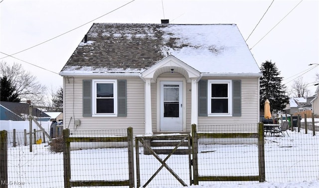 bungalow-style home featuring a fenced front yard, a gate, and a shingled roof