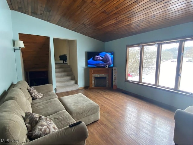 living room with a wealth of natural light, stairway, wood finished floors, and vaulted ceiling