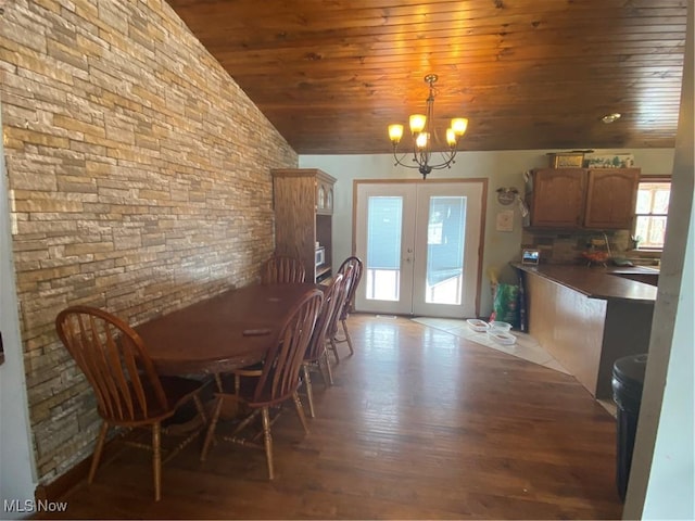 unfurnished dining area featuring light wood finished floors, lofted ceiling, french doors, wooden ceiling, and an inviting chandelier