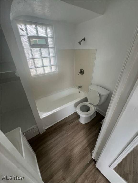 bathroom with shower / washtub combination, toilet, and wood finished floors