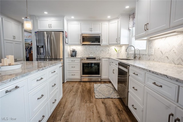 kitchen with dark wood finished floors, tasteful backsplash, appliances with stainless steel finishes, white cabinetry, and a sink