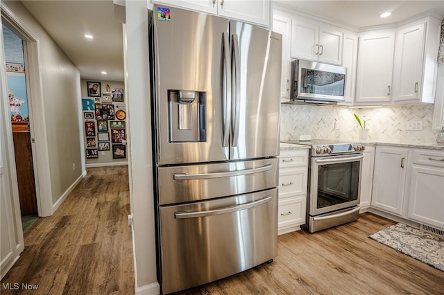 kitchen with appliances with stainless steel finishes, white cabinetry, and light wood-style floors