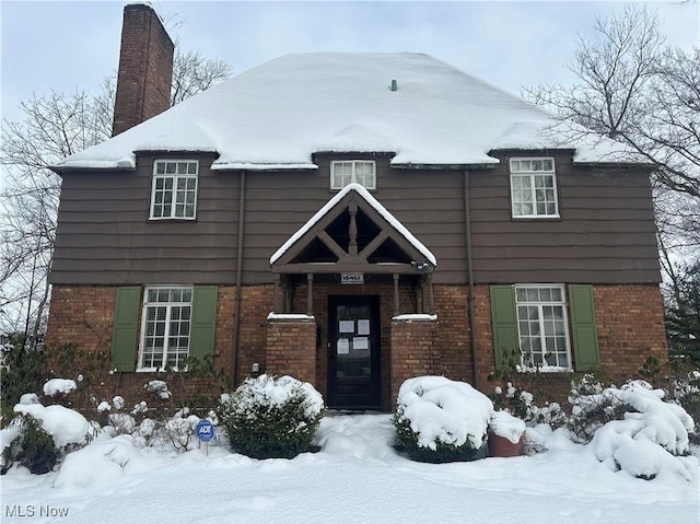 view of front facade featuring brick siding and a chimney