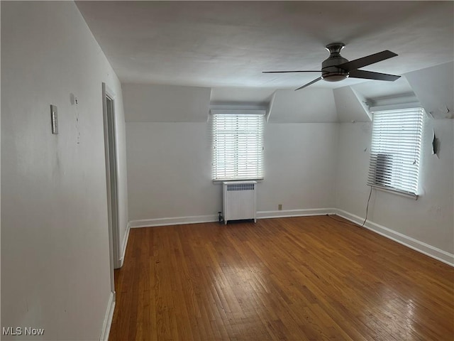 unfurnished room featuring a ceiling fan, radiator heating unit, baseboards, and wood finished floors