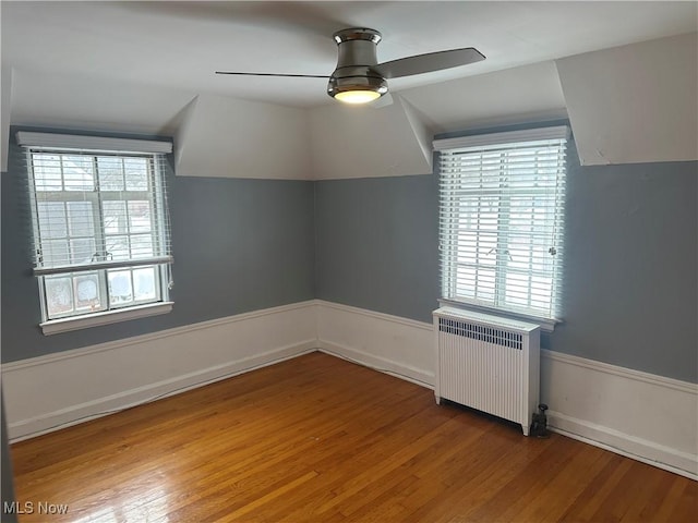 bonus room featuring lofted ceiling, plenty of natural light, radiator heating unit, and wood finished floors