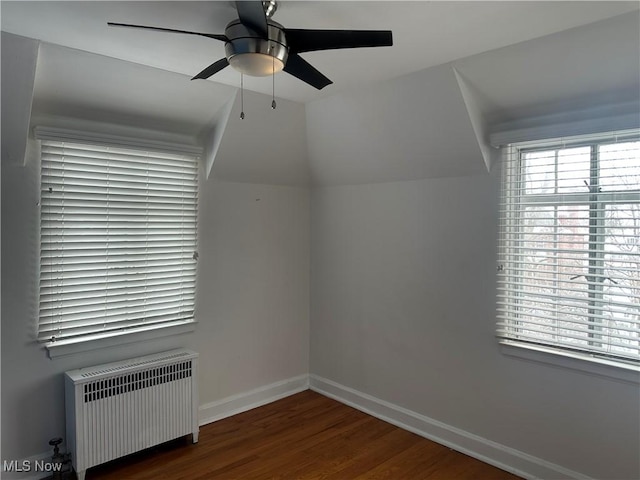 additional living space with lofted ceiling, ceiling fan, wood finished floors, baseboards, and radiator heating unit