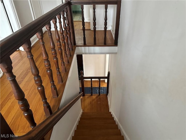 staircase featuring baseboards and wood finished floors