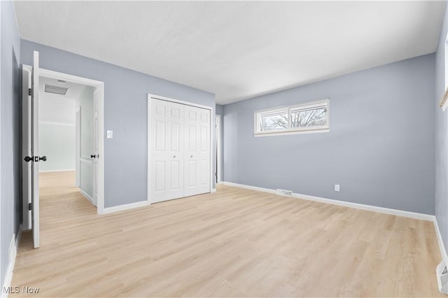 unfurnished bedroom with baseboards, a closet, visible vents, and light wood-style floors