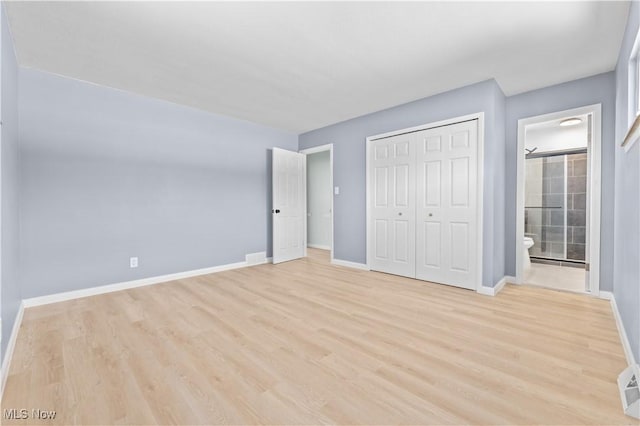 unfurnished bedroom featuring ensuite bathroom, light wood finished floors, a closet, and baseboards