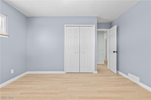 unfurnished bedroom with light wood-style flooring, a closet, visible vents, and baseboards