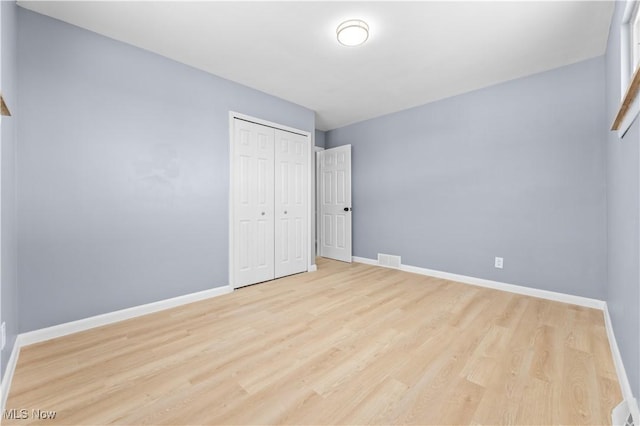 unfurnished bedroom featuring a closet, light wood-type flooring, visible vents, and baseboards