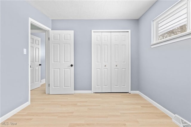 unfurnished bedroom with visible vents, light wood-style flooring, and baseboards