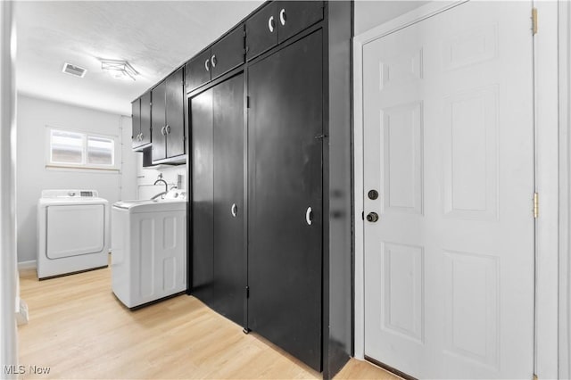 clothes washing area featuring cabinet space, visible vents, light wood finished floors, and separate washer and dryer