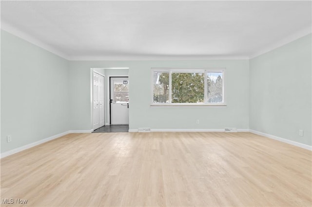 spare room featuring light wood-type flooring, a wealth of natural light, and baseboards