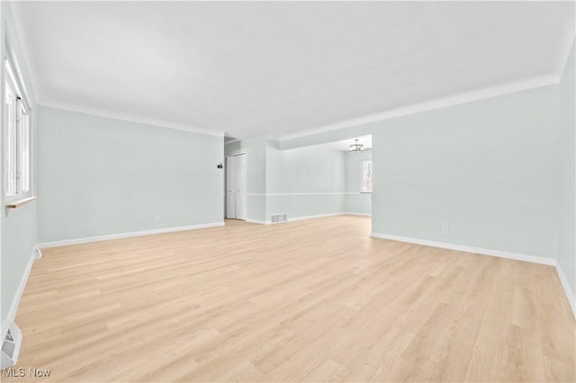 spare room featuring baseboards, crown molding, visible vents, and light wood-style floors