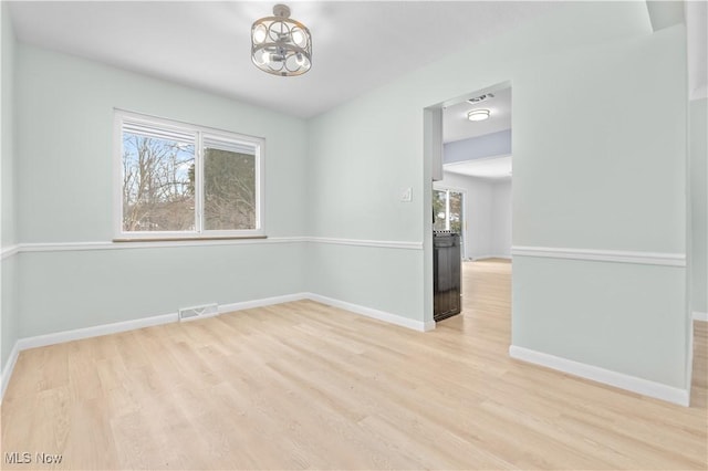 empty room featuring a healthy amount of sunlight, visible vents, baseboards, and light wood finished floors