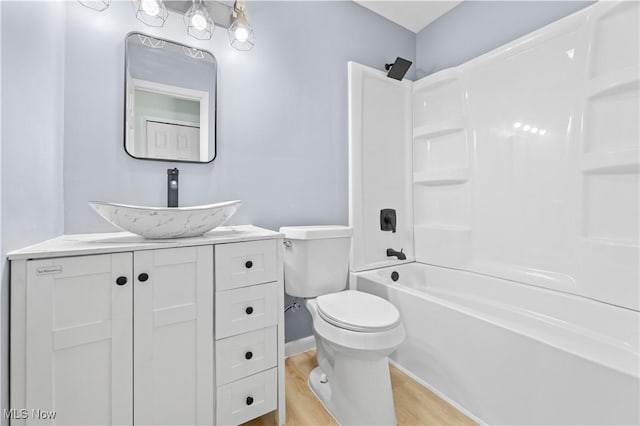 bathroom with shower / bath combination, baseboards, toilet, wood finished floors, and vanity