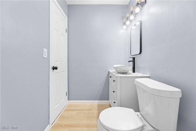 bathroom with baseboards, vanity, toilet, and wood finished floors