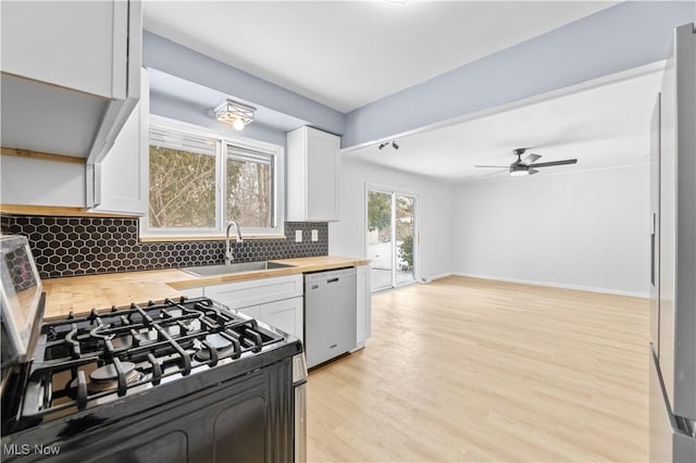 kitchen with a sink, wood counters, white cabinets, stainless steel dishwasher, and black gas range oven