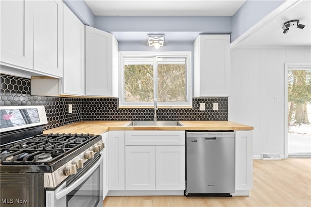 kitchen with a sink, visible vents, wood counters, white cabinets, and appliances with stainless steel finishes