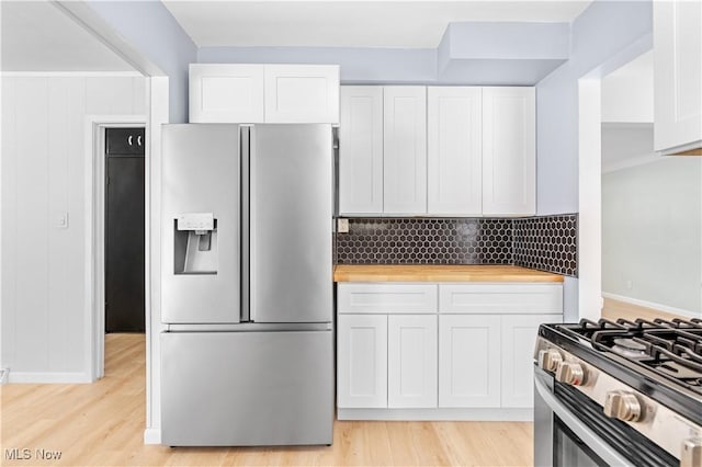 kitchen with stainless steel appliances, white cabinets, light wood-style floors, and backsplash