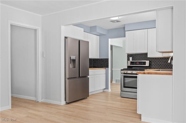 kitchen featuring stainless steel appliances, wooden counters, light wood-style floors, white cabinets, and a sink