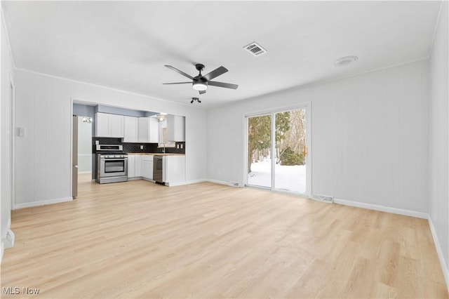 unfurnished living room featuring a sink, light wood-style floors, visible vents, and a ceiling fan