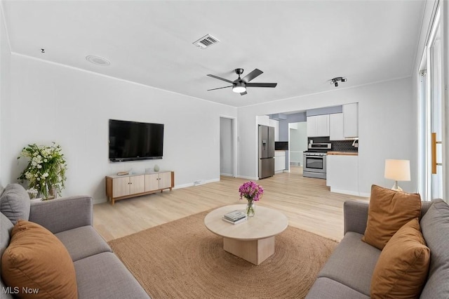 living room featuring a ceiling fan, visible vents, and light wood-style floors