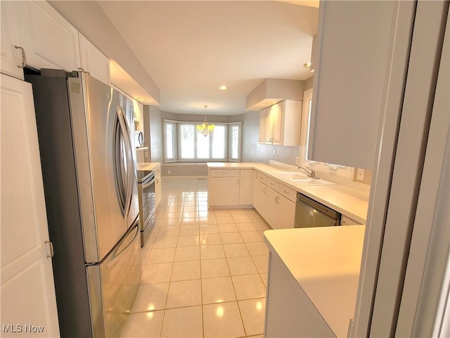 kitchen featuring stainless steel appliances, a sink, white cabinets, light countertops, and pendant lighting