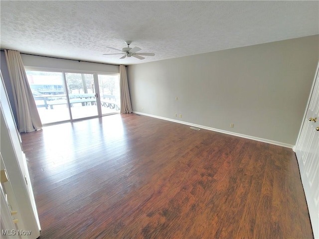 empty room with visible vents, baseboards, dark wood finished floors, ceiling fan, and a textured ceiling