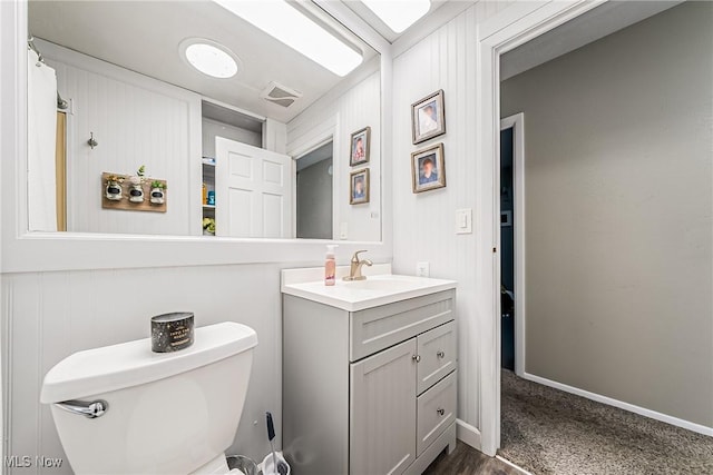 bathroom with toilet, visible vents, vanity, and baseboards