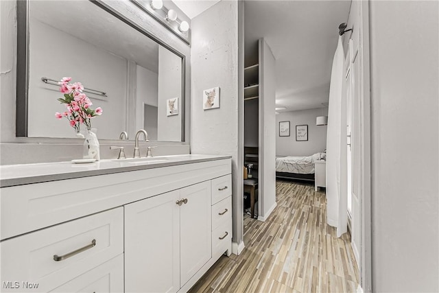 bathroom with wood finished floors, connected bathroom, and vanity