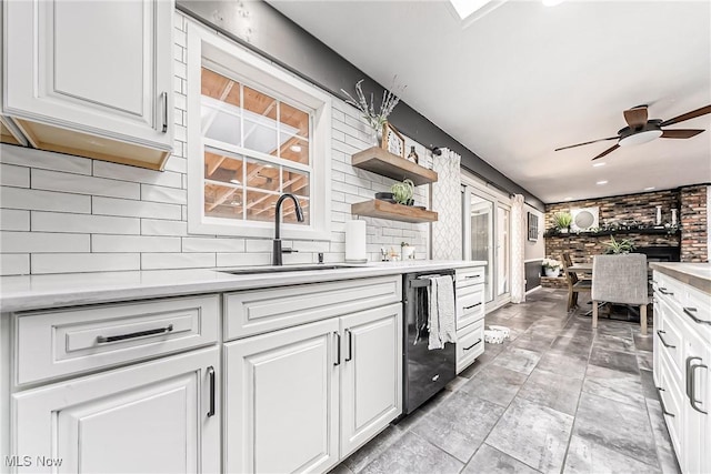 kitchen featuring dishwasher, light countertops, a sink, and white cabinetry