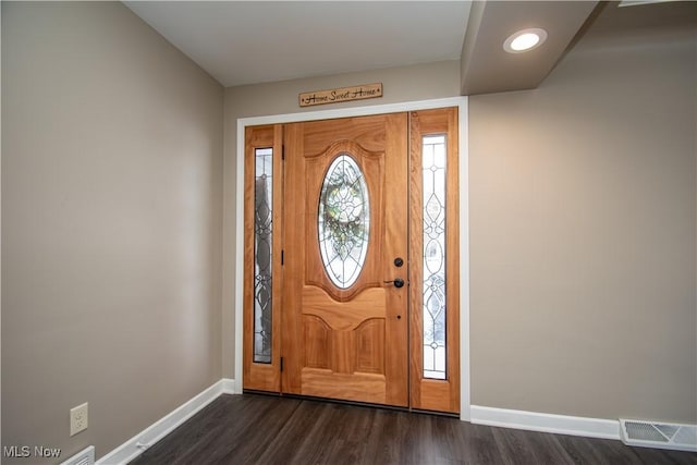 foyer with dark wood-type flooring, visible vents, and baseboards