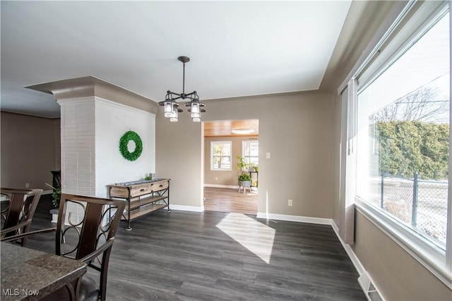 dining space with dark wood-style floors, a chandelier, and baseboards