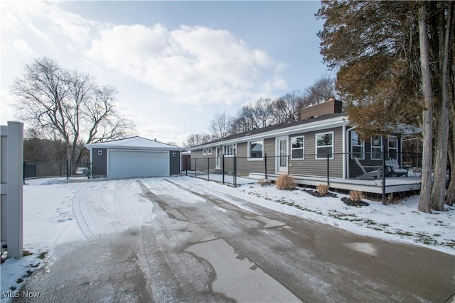 view of front of house featuring a wooden deck, a detached garage, a chimney, and an outbuilding