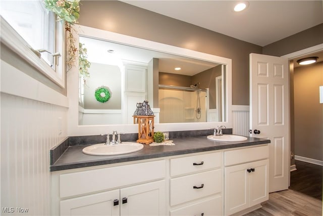 full bathroom featuring a stall shower, a sink, and double vanity