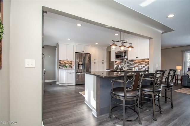 kitchen with pendant lighting, stainless steel appliances, a breakfast bar area, and white cabinets