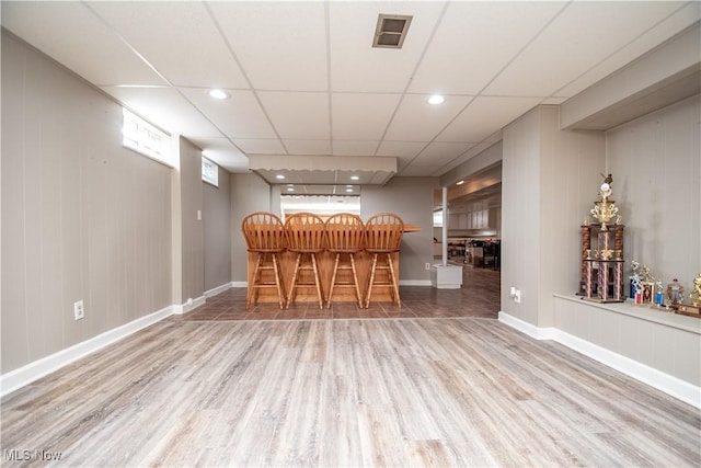 bar with a dry bar, baseboards, visible vents, a drop ceiling, and wood finished floors