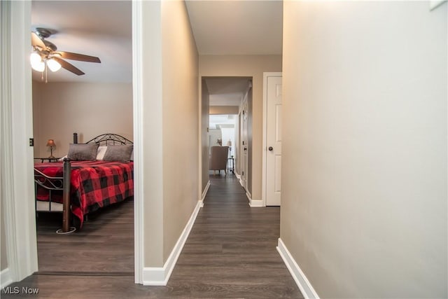 hallway featuring dark wood-type flooring and baseboards