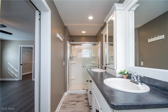 full bathroom featuring a stall shower, a sink, and wood finished floors