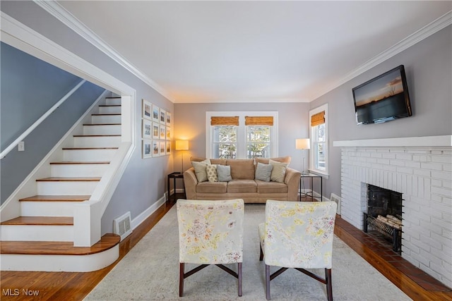 living room with stairway, visible vents, dark wood finished floors, and crown molding